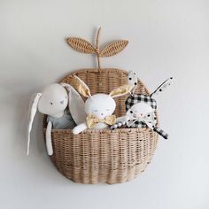 two stuffed animals in a wicker basket hanging on the wall next to another stuffed animal