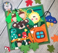 an assortment of felt toys on a wooden surface with leaves and flowers around them,