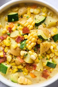 a white bowl filled with corn, potatoes and zucchini on top of a table