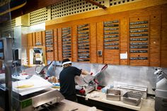 a man working in a restaurant kitchen with lots of signs on the wall behind him