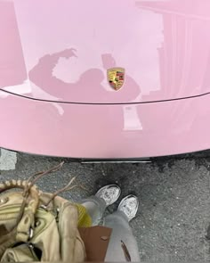 a pink car parked next to a person holding a cell phone