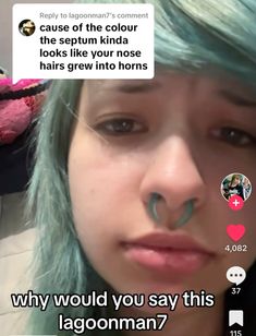 a girl with blue hair and piercings on her nose is looking at the camera