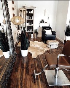 a chair and mirror in a room with wood flooring on the floor, plants are placed next to each other