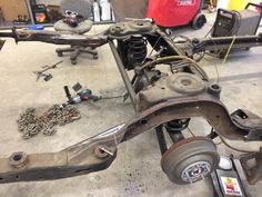 the front end of a car being worked on in a garage with tools and other items