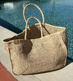 a straw bag sitting on the edge of a swimming pool