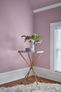 a vase with flowers sitting on top of a small table in front of a window