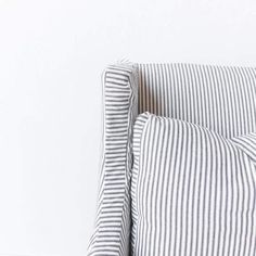 a white and black striped pillow on the back of a chair in front of a white wall