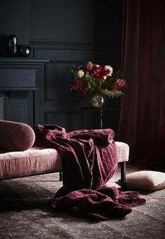 an image of a bed with a red blanket on it and flowers in the background