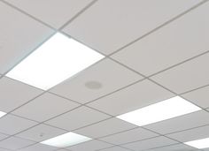 an empty room with white ceiling tiles and lights