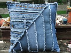 a blue jean pillow sitting on top of a wooden bench