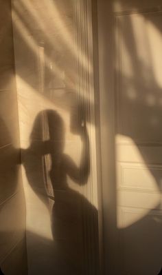 the shadow of a person standing in front of a door with their arm extended up