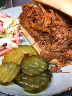 a pulled pork sandwich with pickles and coleslaw