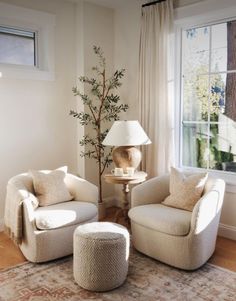 a living room with two chairs and a lamp on the table in front of a window