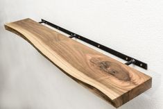 a wooden shelf mounted to the side of a wall with black metal brackets on it