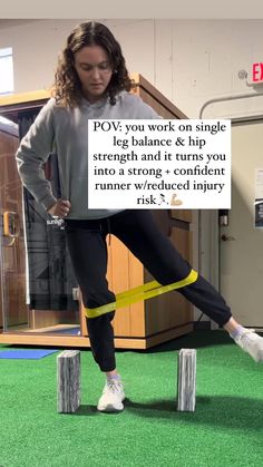 a woman standing on top of two wooden blocks while holding a yellow tape around her ankles