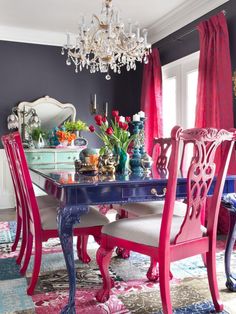 a dining room table with pink chairs and a chandelier hanging from the ceiling