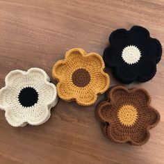 four crocheted flowers sitting on top of a wooden table