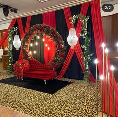 a red couch sitting on top of a black carpeted floor next to a stage