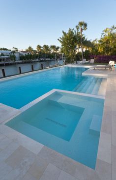 an empty swimming pool with lounge chairs and palm trees in the backgrouds