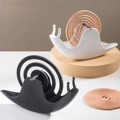 three different types of decorative objects on a table with white and pink accents, one is shaped like a snail