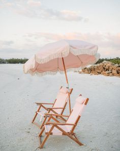 two lawn chairs and an umbrella on the beach