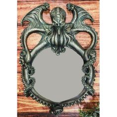 a mirror with an ornate design on the front and back of it, sitting on top of a wooden surface