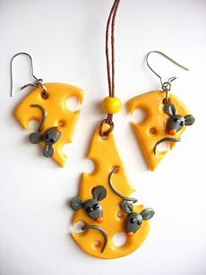 three pieces of cheese with mice on them are hanging from strings and ear wires,