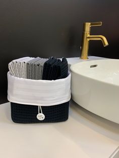 a white sink sitting under a faucet next to a black and white basket