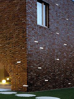 a building made out of bricks with grass in the foreground and light shining on it