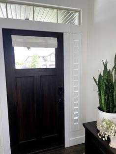 a black front door with a potted plant next to it on a wooden table