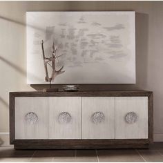 a white and brown sideboard with four drawers in front of a painting on the wall