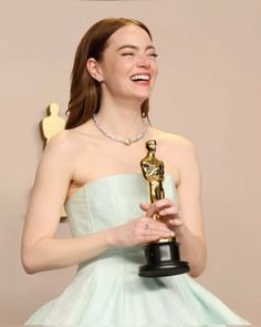 a woman in a blue dress holding an oscar award