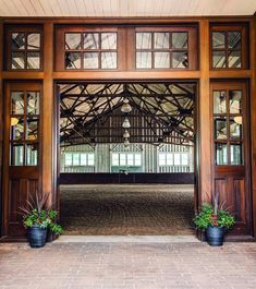 an open wooden door with two potted plants