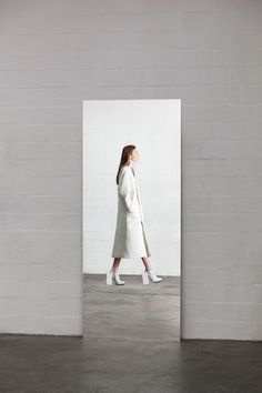 a woman in a white coat walking through an empty room