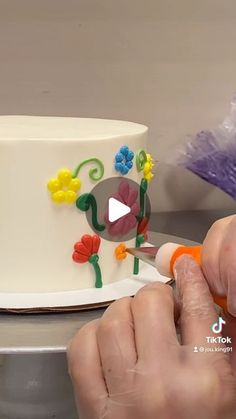 someone is decorating a cake with flowers on it