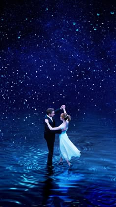 a couple dancing in the water at night with stars on the sky above and behind them