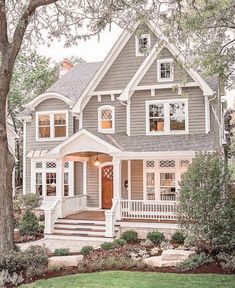 a gray house with white trim on the front porch and stairs leading up to it