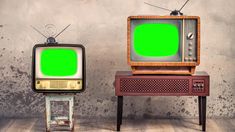 two old tvs with green screen sitting next to each other on wooden flooring