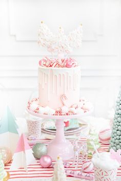 a pink cake sitting on top of a table next to other desserts and decorations