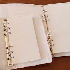 two white notebooks sitting next to each other on top of a wooden table,