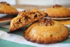 three pastries with walnuts on them sitting on a striped tablecloth next to plates