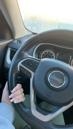 a woman driving a car with the steering wheel and dash light on, while her hand is on the steering wheel