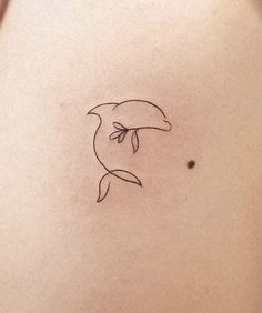 a small dolphin tattoo on the back of a woman's left shoulder and arm