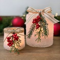 two mason jars decorated with holly and berries