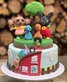 there is a small cake decorated with animals on the top of it and trees in the background