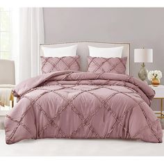 a bed with a pink comforter and white pillows