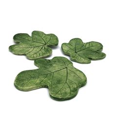 three green leaf shaped dishes on a white surface