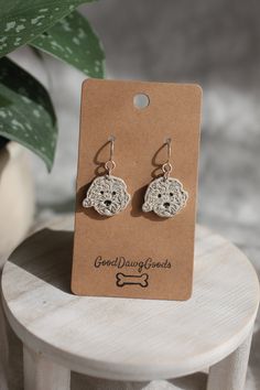 a pair of earrings sitting on top of a wooden table next to a potted plant