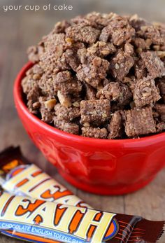 a red bowl filled with brownies next to an orange candy bar on top of a wooden table