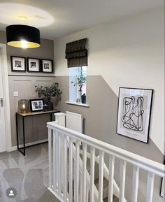 a hallway with stairs and pictures hanging on the wall above it's railings